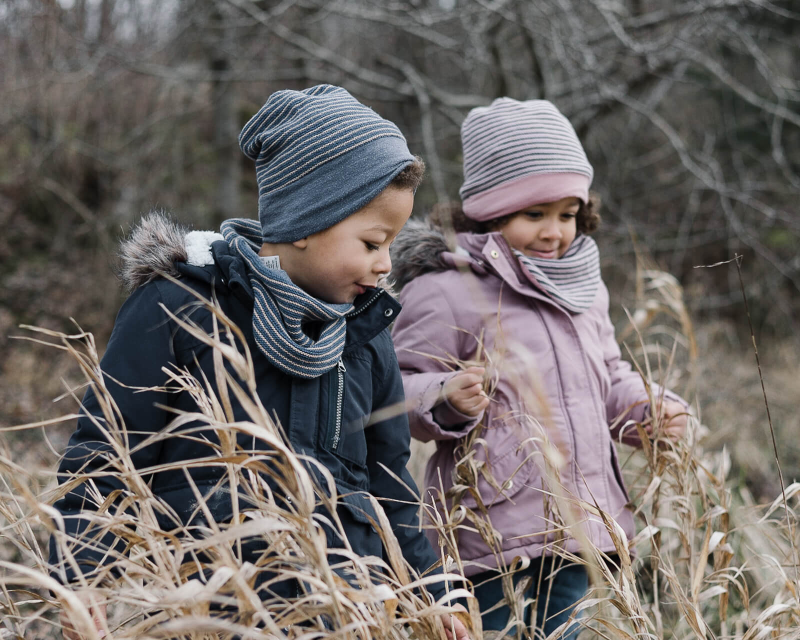 Ein Mädchen und ein Junge stehen im Winter im hohen Gras