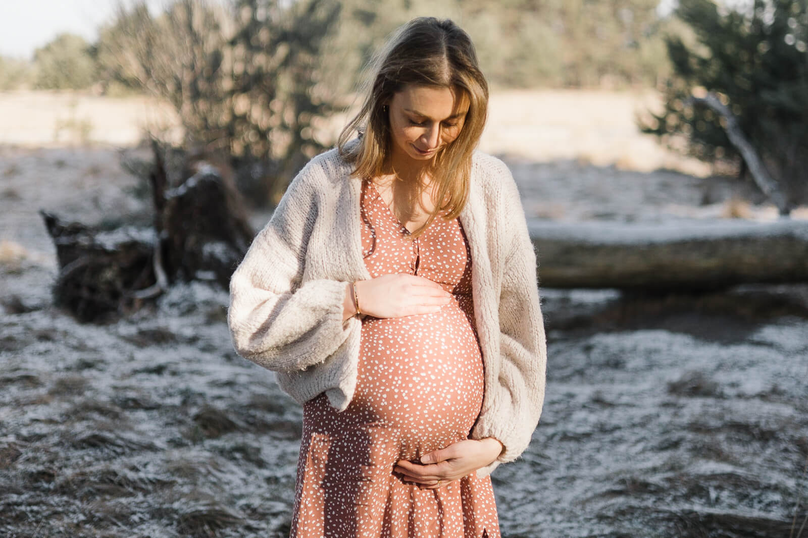 Eine schwangere Frau schaut liebevoll auf ihren kugelrunden Babybauch