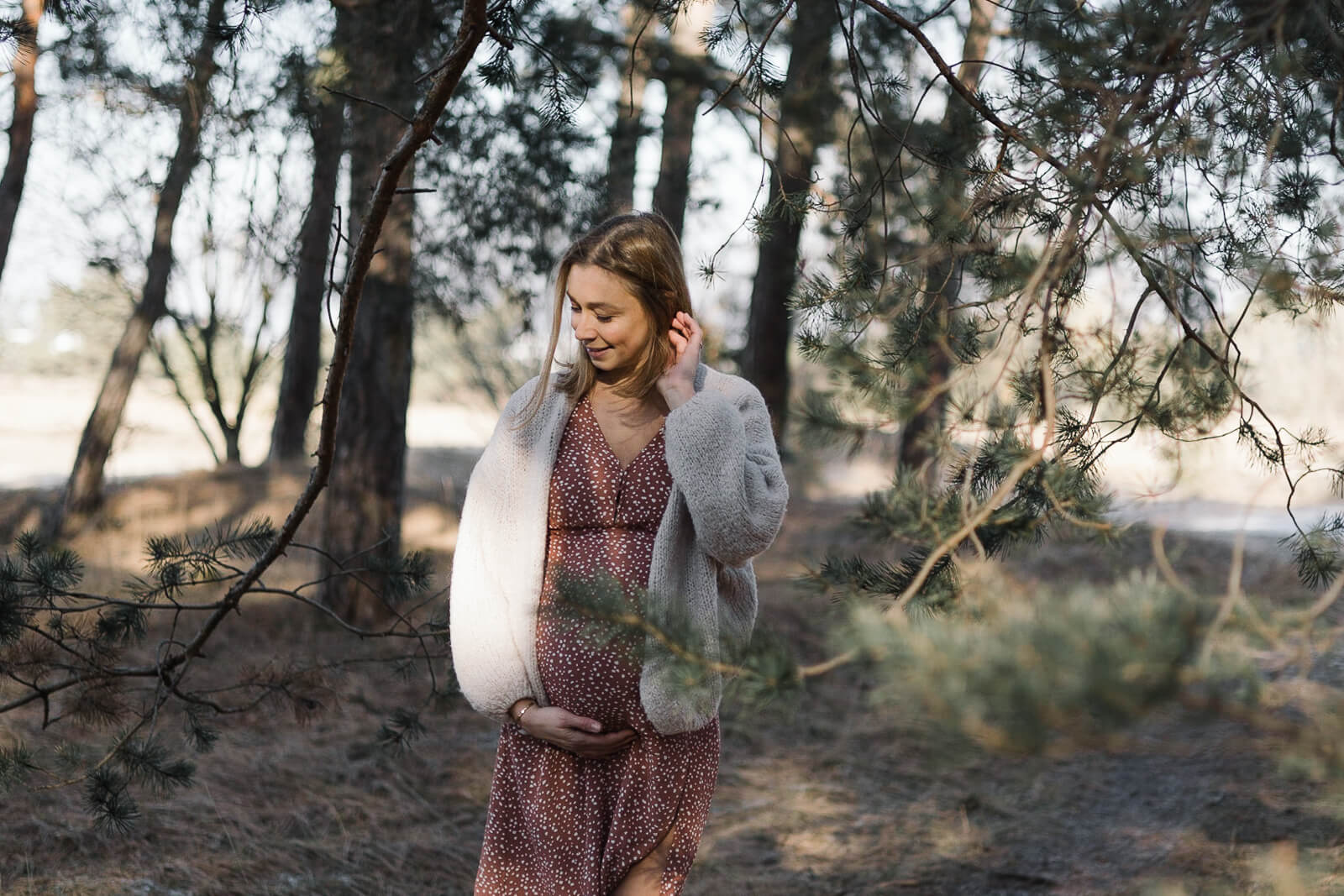 Eine schwangere Frau steht an einem sehr kalten Wintertag im Wald