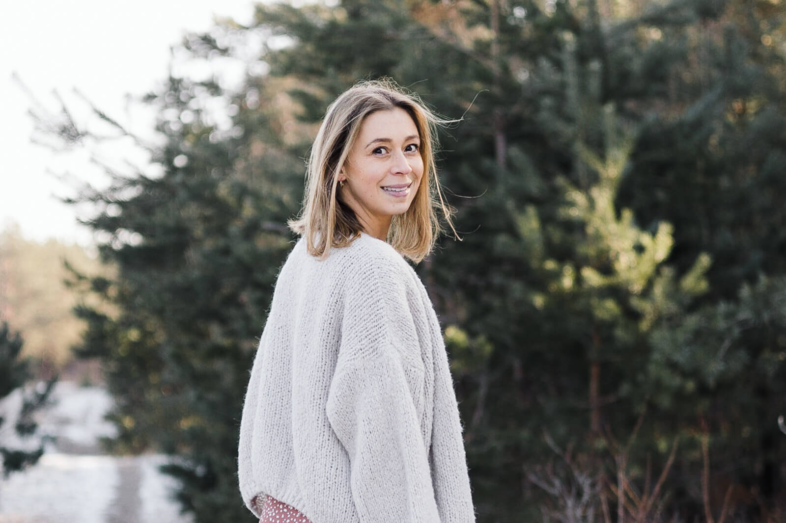 Eine schwangere Frau lächelt über ihre Schulter hinweg