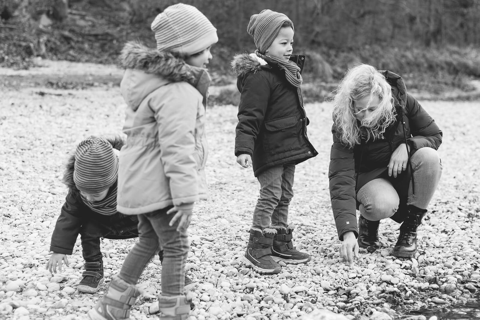 Eine Mutter spielt mit ihren drei Kindern im Flussbett der Isar