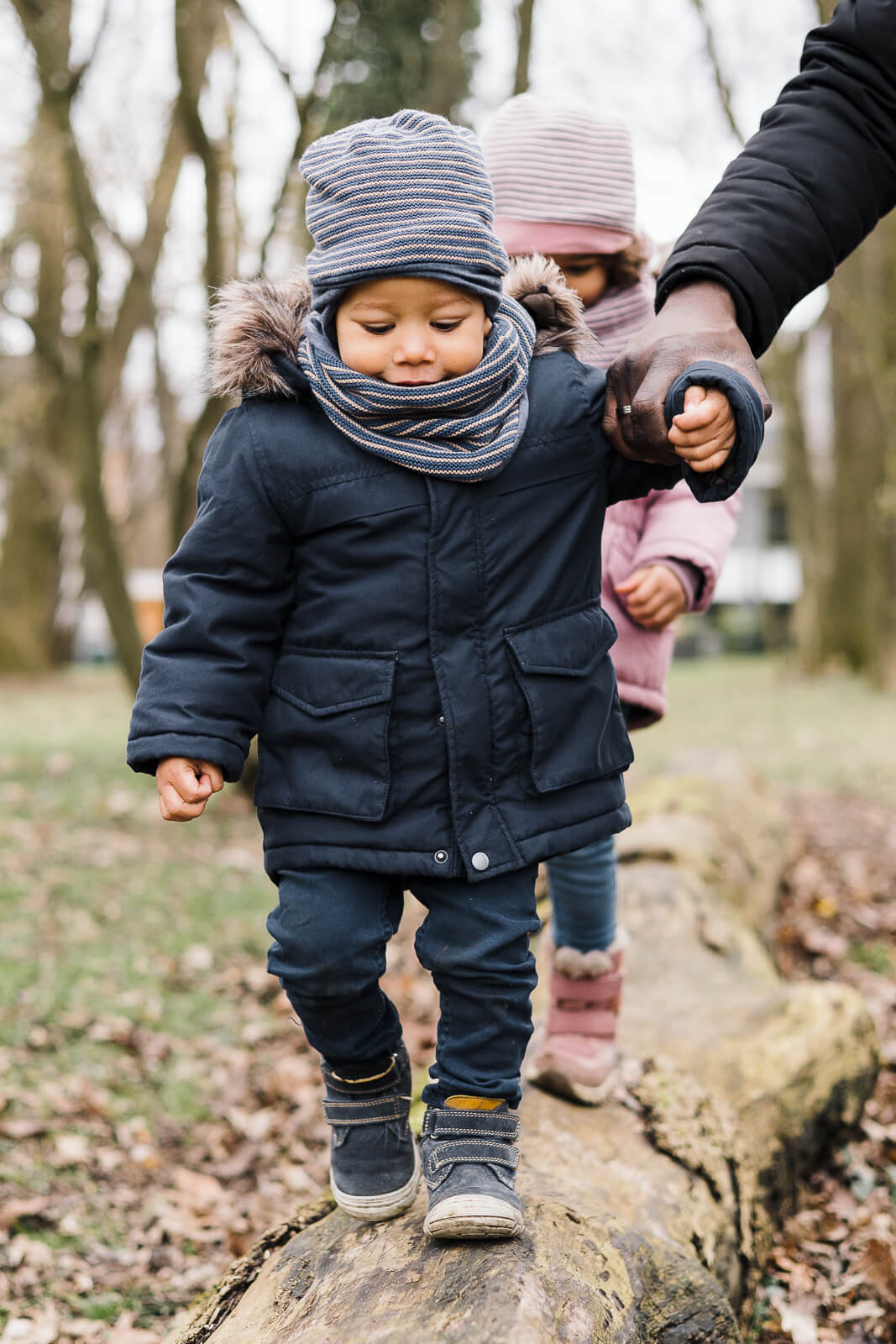 Zwei kleine Kinder balancieren über einen umgefallenen Baumstamm
