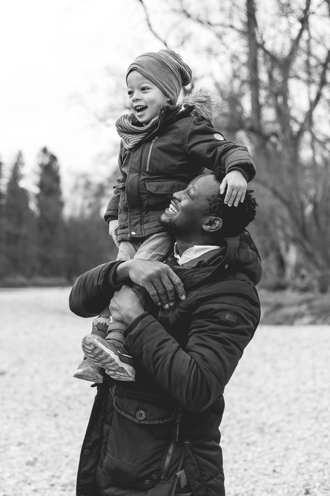 Ein Familienvater trägt seinen Sohn stolz auf einer Schulter