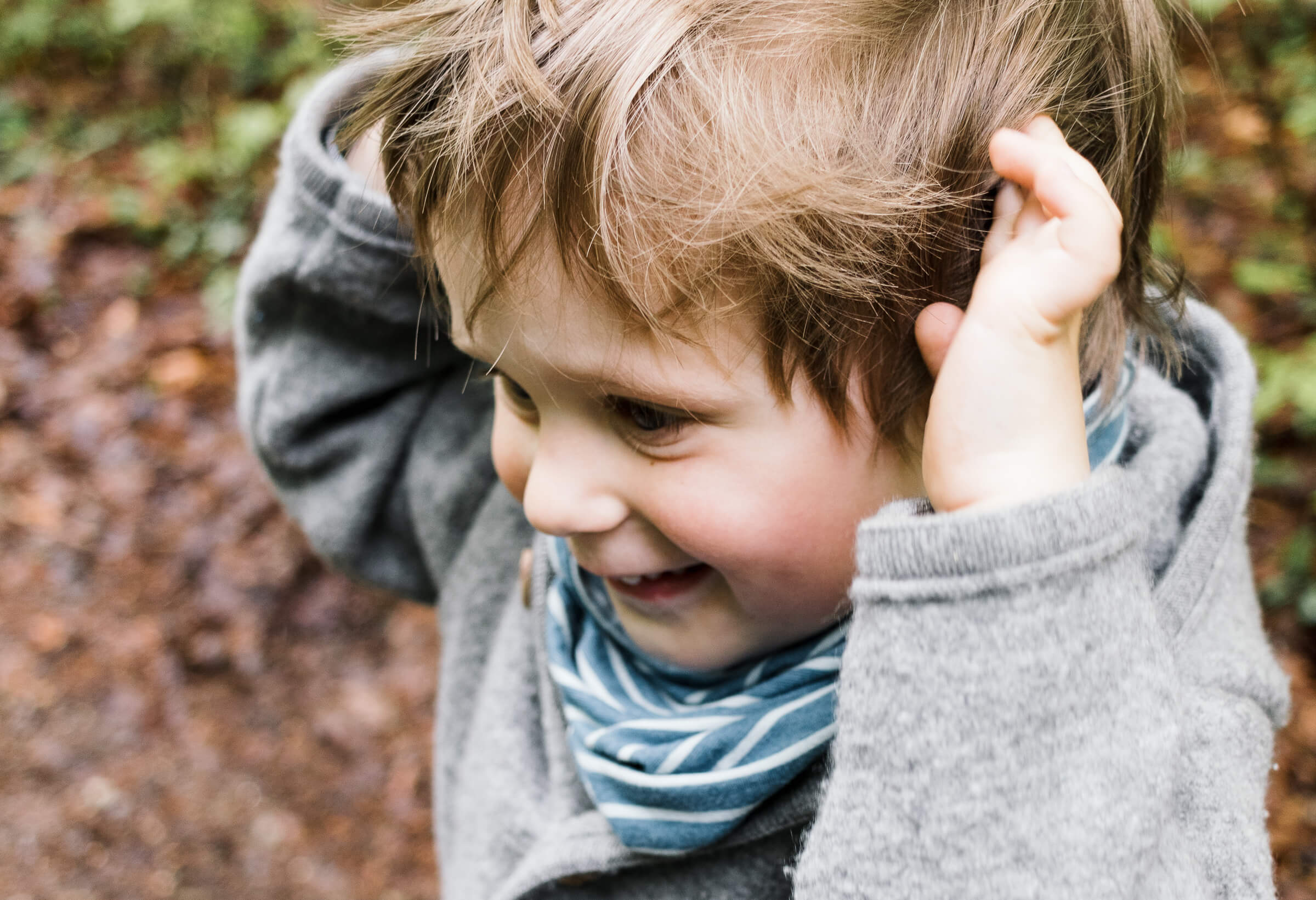 Ein kleiner Junge strubbelt durch die Haare und lacht