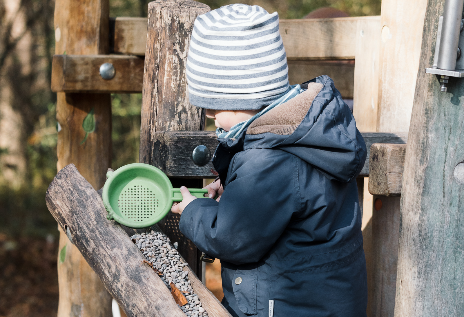 Ein kleiner Junge beobachtet fallende Steine auf einem Klettergerüst