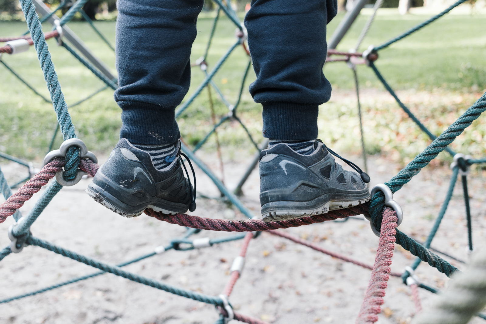 Ein kleiner Junge ist auf ein Klettergerüst auf einem Spielplatz geklettert
