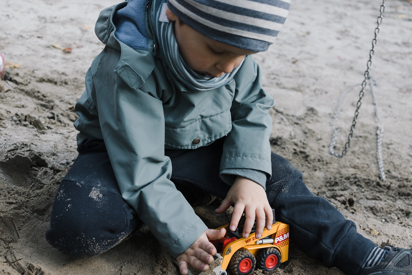 Ein kleiner Junge spielt mit einem Sandspielzeug im Sand